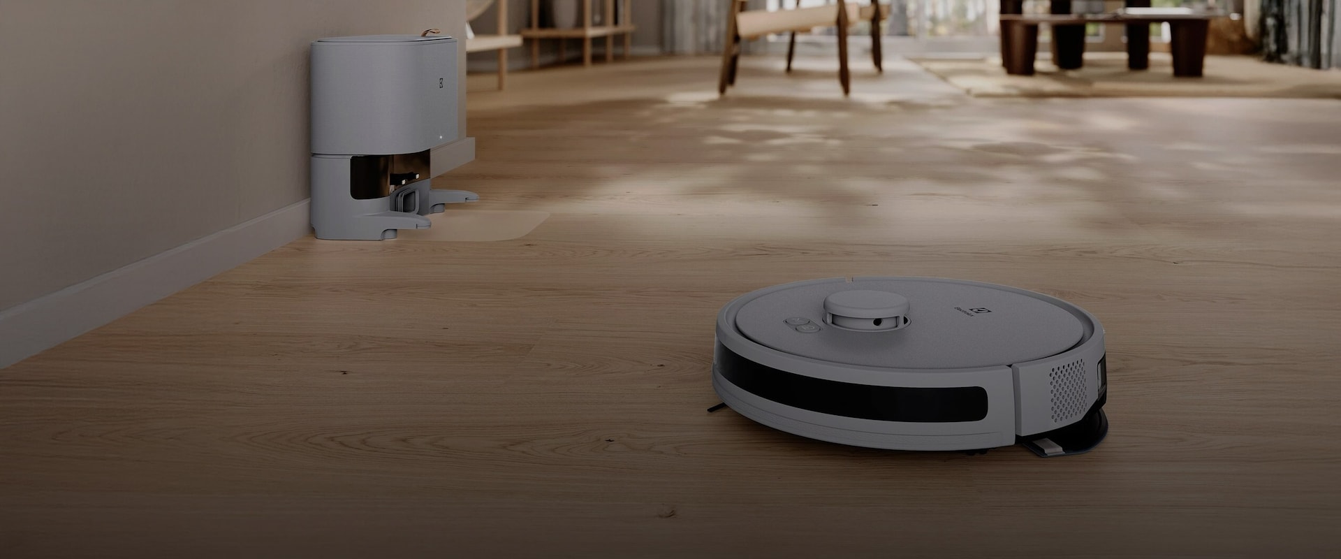 Selvgående Electrolux-robotstøvsuger som rengjør et lyst tregulv i en åpen og moderne stue.